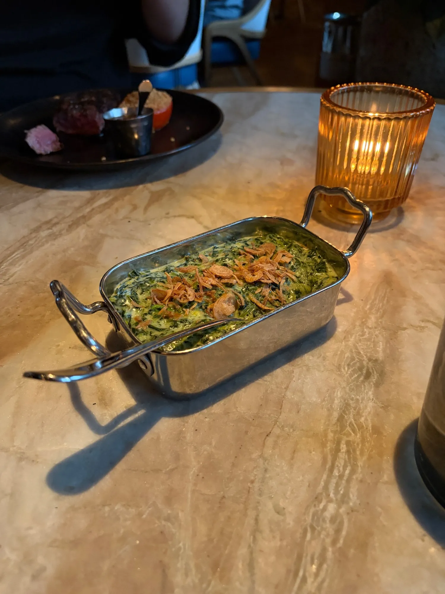 Creamed spinach topped with crisp pieces sits in a rectangular metal serving dish.