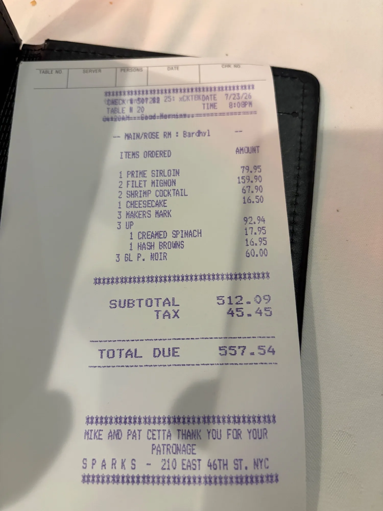 A printed receipt from Sparks listing sirloin, filet mignon, shrimp cocktail, cheesecake, drinks and sides with subtotal, tax and total.